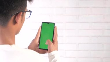 Genç adam akıllı telefonu kapalı alanda kullanıyor. 