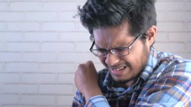 Genç hasta adam burnunu ve ağzını koluyla kapatıyor..