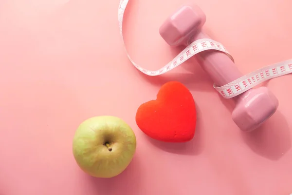 Conceito de fitness com haltere e fita métrica em rosa — Fotografia de Stock