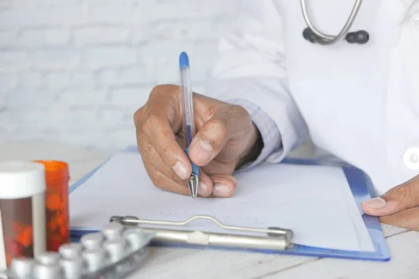 Doctor hand writing prescription on desk, close up. — Stock Photo, Image