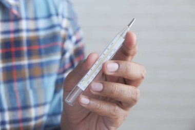 Beyaz arka planda tıbbi termometre tutan adam. 