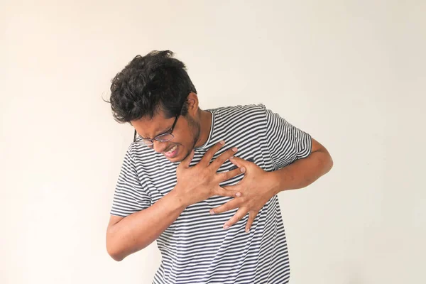 Ung man lider smärta i hjärtat och hålla bröstet med handen — Stockfoto