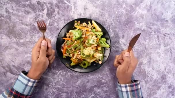 Young man with fork waiting in from on a plate full of vegetable — Stock Video