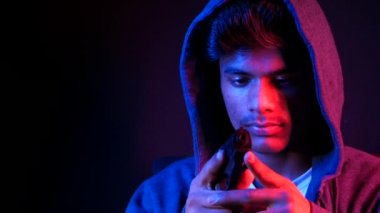 Kapüşonlu adamın elinde silah var. Siyah üzerine izole edilmiş. 