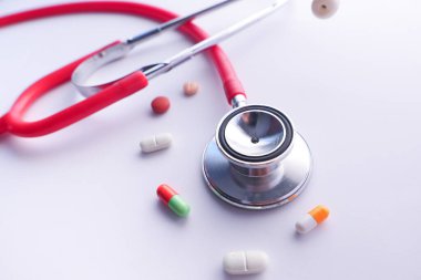 Beyaz arka planda hapları ve steteskopu kapat 