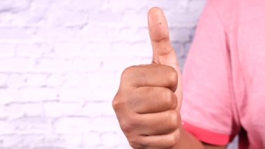 Adam eli beyaz arka planda baş parmağını gösteriyor 
