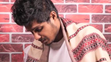 Genç hasta adam kanepede otururken baş ağrısı çekiyor. 