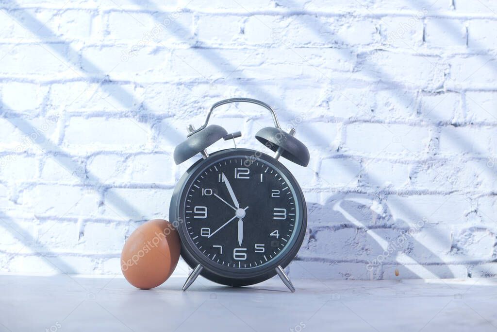 alarm clock and egg on table with copy space