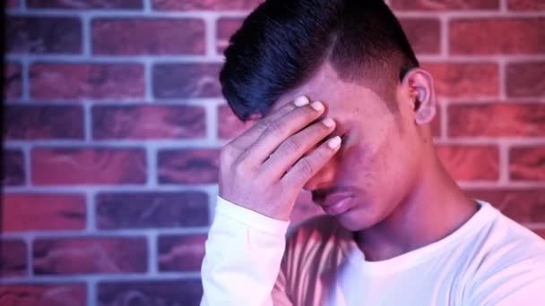Молодой человек расстроен и страдает головной болью, закрыть — стоковое видео