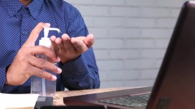İş adamı ofis masasında dezenfektan jeli kullanıyor. 
