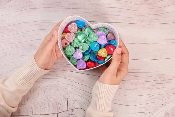 Top view of womens hand holding a gift box full of candy — Stock Photo, Image