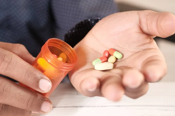 İlaç kutusundan dökülen ilaçlı adam eli. 