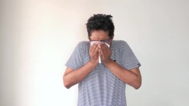 Genç hasta adam günlük kıyafetlerle öksürüyor ve hapşırıyor. 