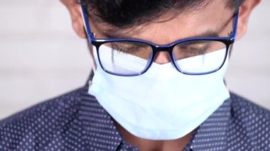 Duvara karşı koruyucu maskeli genç bir adam. 