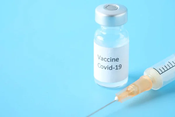 Закрытие коронавирусной вакцины и шприца на синем фоне — стоковое фото