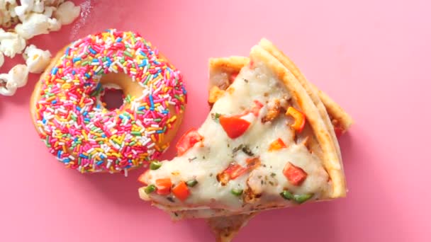 Fatia de pizza de queijo em um prato, rosquinhas e pipocas em rosa — Vídeo de Stock