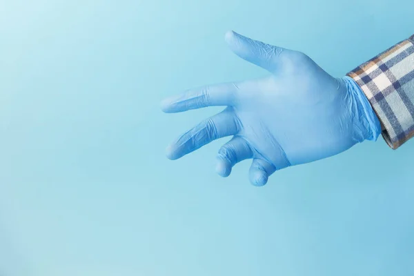 Doktor ruka s rukavicí na modrém pozadí. — Stock fotografie