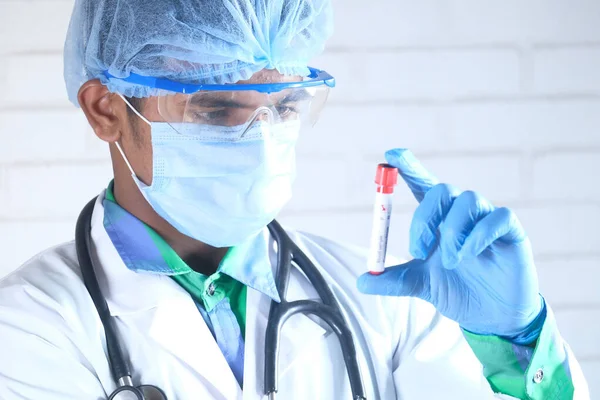 Χέρι σε μπλε ιατρικά γάντια που κρατούν σωλήνα εξέταση αίματος — Φωτογραφία Αρχείου