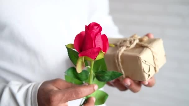 Mann hält Geschenkbox und Rosenblume in der Hand — Stockvideo