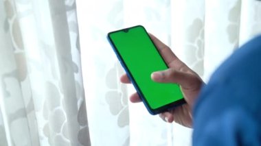 Akıllı telefonu kapalı alanda kullanan genç bir adamın dikiz görüntüsü 