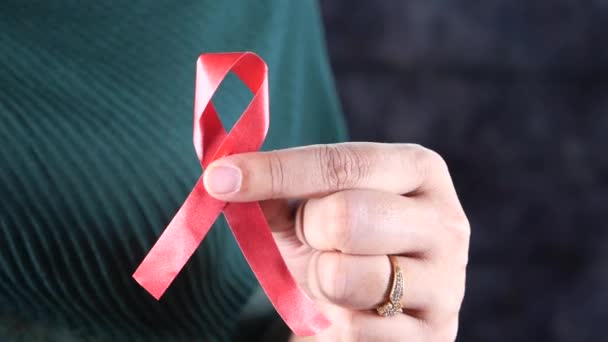 Mulheres mão segurando fita HIV vermelho isolado em preto — Vídeo de Stock