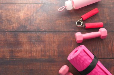  Pembe dambıl, egzersiz paspası ve ahşap arka planda su şişesi. 