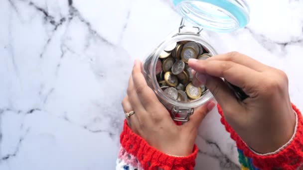 Shora pohled na ženy ruční ukládání mincí ve sklenici — Stock video