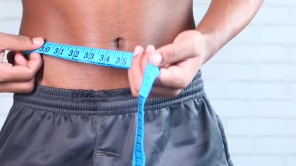 Giovane uomo che misura la sua vita con un metro a nastro, da vicino. — Video Stock