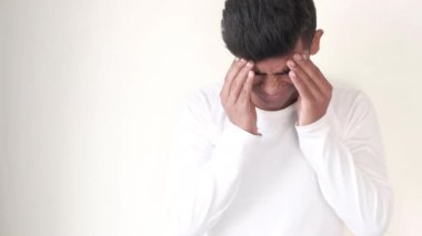 Genç adam yüzünü baş ağrısı çeken ellerle örttü., 