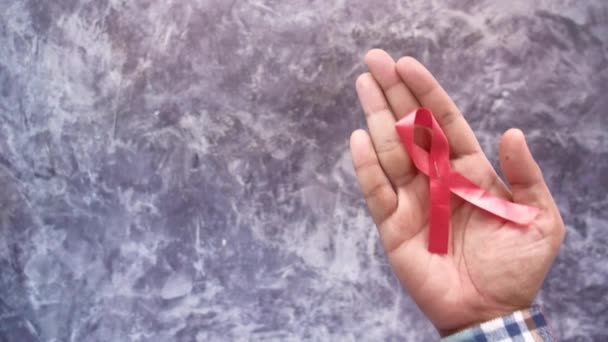 Mão segurando fita vermelha HIV de cima para baixo — Vídeo de Stock