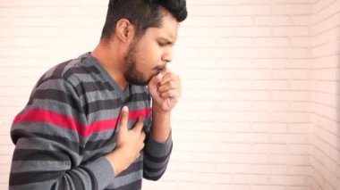  Genç Asyalı adam öksürüyor ve hapşırıyor. 
