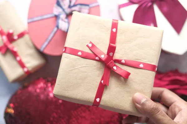 Vista superior de la mano del hombre sosteniendo una caja de regalo en la mesa — Foto de Stock