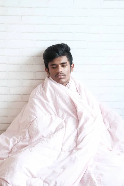 Zieke man met deken zittend op bed — Stockfoto