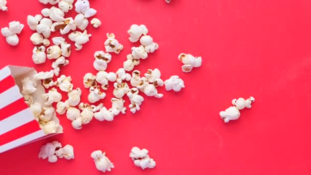 Popcorn morsen uit een container op rode achtergrond — Stockvideo