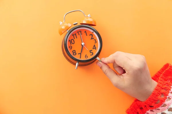 Mujer mano celebración despertador reloj naranja fondo , —  Fotos de Stock