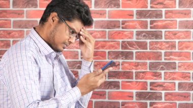 Ciddi bir adamın sandalyeye oturup akıllı telefon kullanmasının yan görüntüsü. 