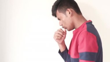  Genç hasta adam öksürüyor ve elini göğsüne koyuyor. 