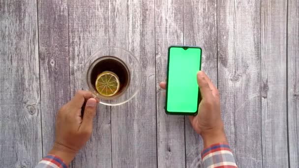Vista dall'alto dell'uomo utilizzando smart phone e bere tè sul tavolo — Video Stock