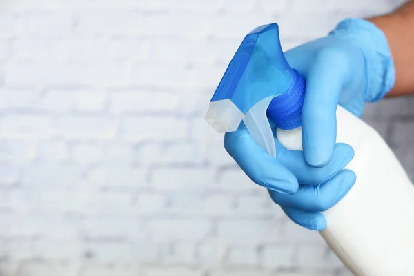 Hand in blauwe rubberen handschoenen met spuitfles en kopieerruimte — Stockfoto