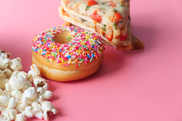 Käse-Pizza auf einem Teller, Donuts und Popcorn auf rosa — Stockfoto