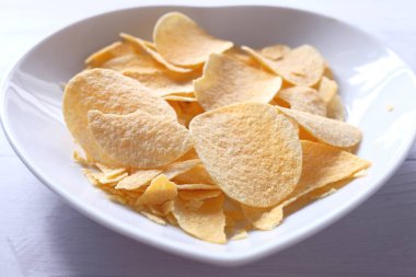 Ahşap zemin üzerinde patates cipsi olan bir kase. .
