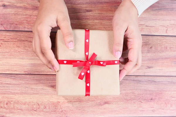 Top view of women hand holding a gift box on table — Stock Photo, Image