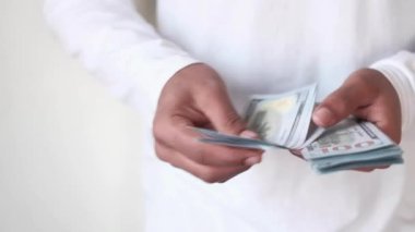 Bir adamın eli 100 dolar nakit sayıyor. 