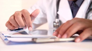 Beyaz önlüklü doktor dijital tablet kullanıyor.