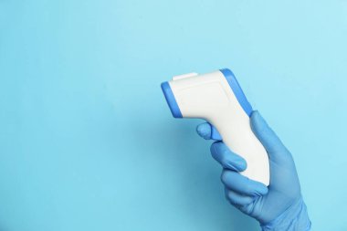 Mavi arkaplanda sıcaklığı ölçmek için el ele tutuşan kızılötesi termometre 