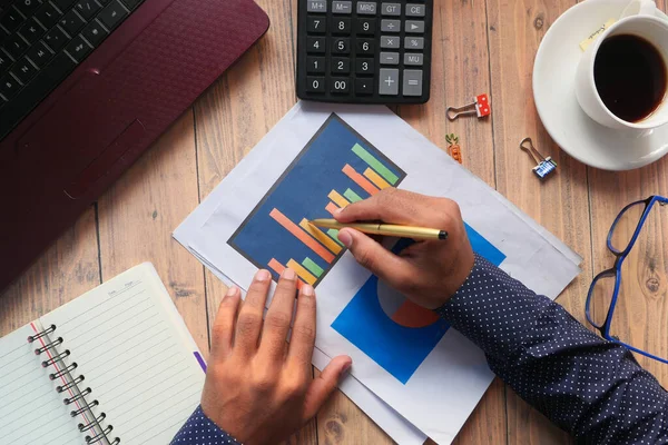 Vue du dessus de la main de l'homme avec stylo analysant le tableau financier sur papier — Photo