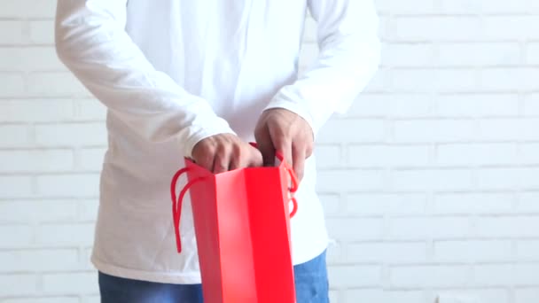 Junger Mann steckt Geschenk in Einkaufstasche — Stockvideo