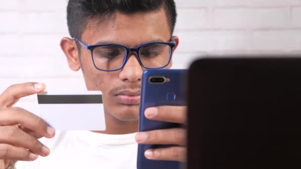 Fiatal ázsiai férfi gazdaság hitelkártya és okos telefon vásárlás online — Stock videók