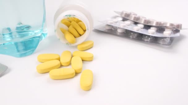 Pillole colorate, blister e bicchiere d'acqua su sfondo bianco — Video Stock