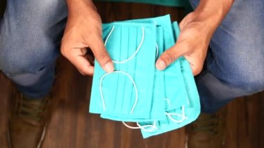  Cerrahi yüz maskesi tutan adamın üst görüntüsü.